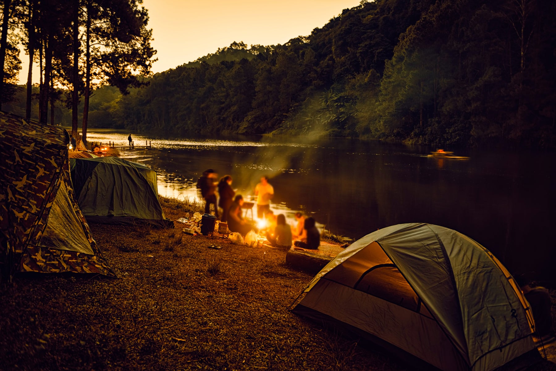 outdoor photo of people around a campfire at dusk.