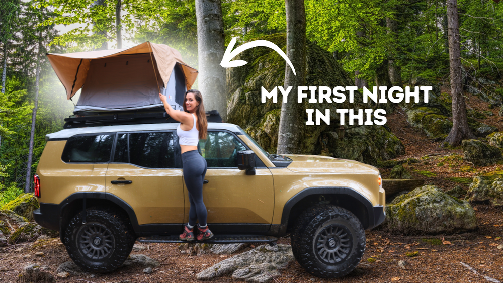 Janna beside her 2025 Toyota Land Cruiser 250 with a Front Runner rack and open rooftop tent in a wooded campsite; video thumbnail.