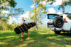 Camper carrying the packed Oztent RV-5 tent at a grassy campsite