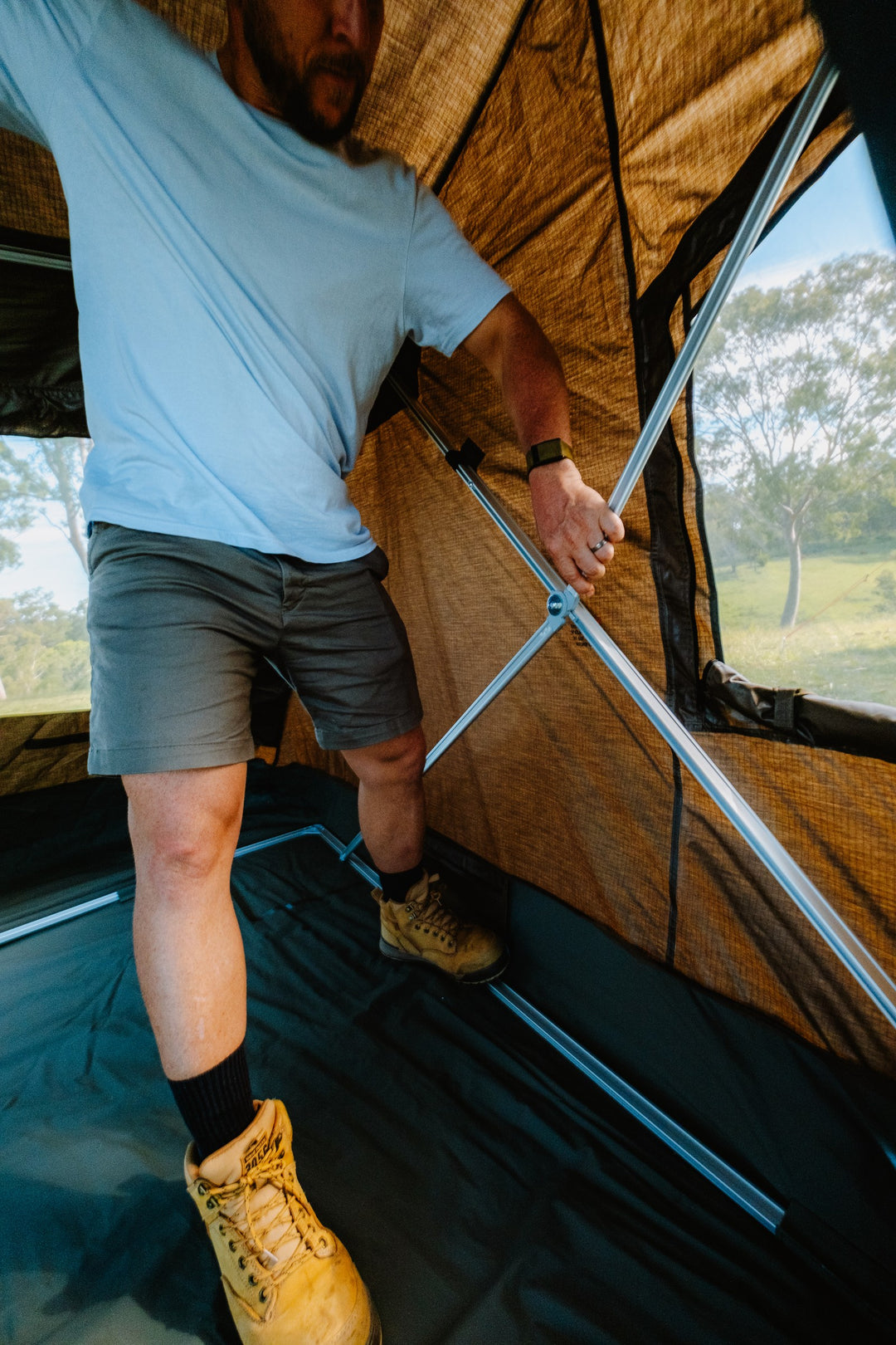 Camper operating the Oztent RV-5 internal folding frame during setup