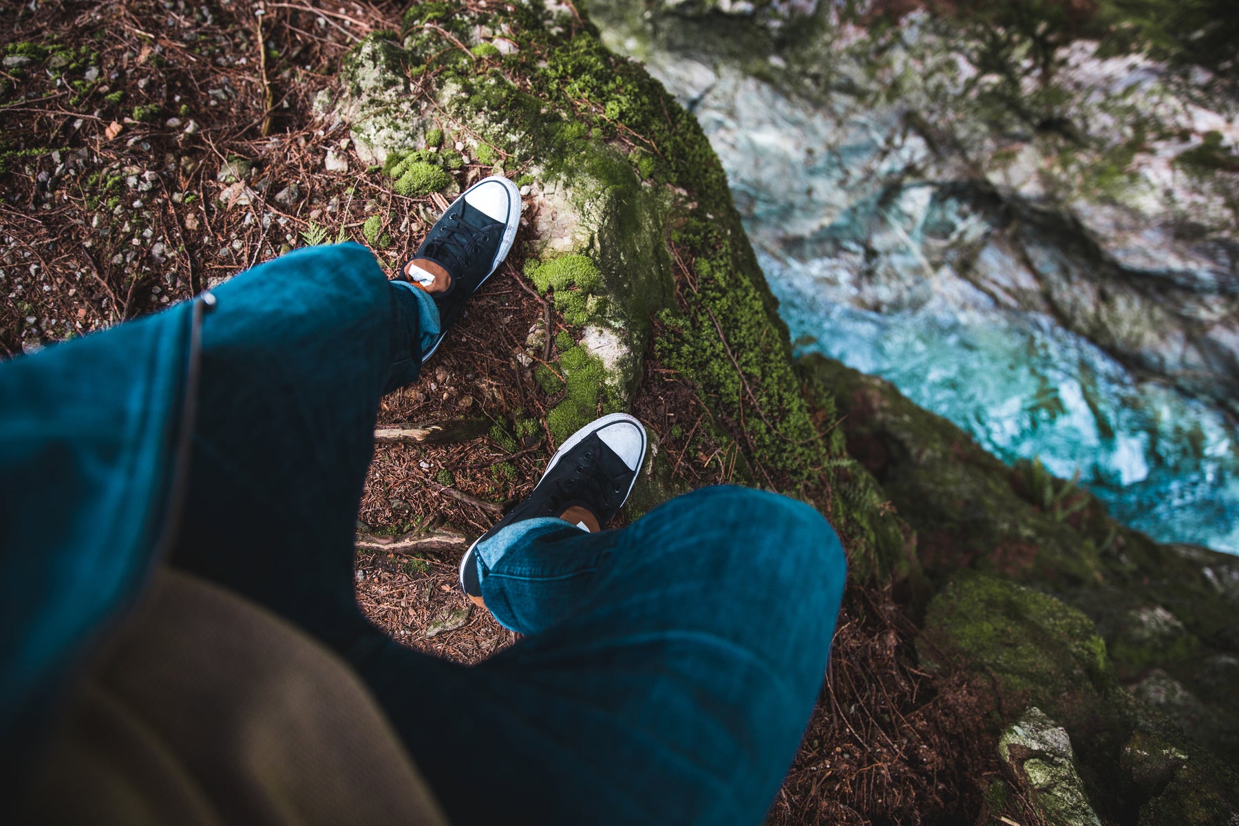outdoor photo of a person's feet overlooking a steep ravine with water below.
